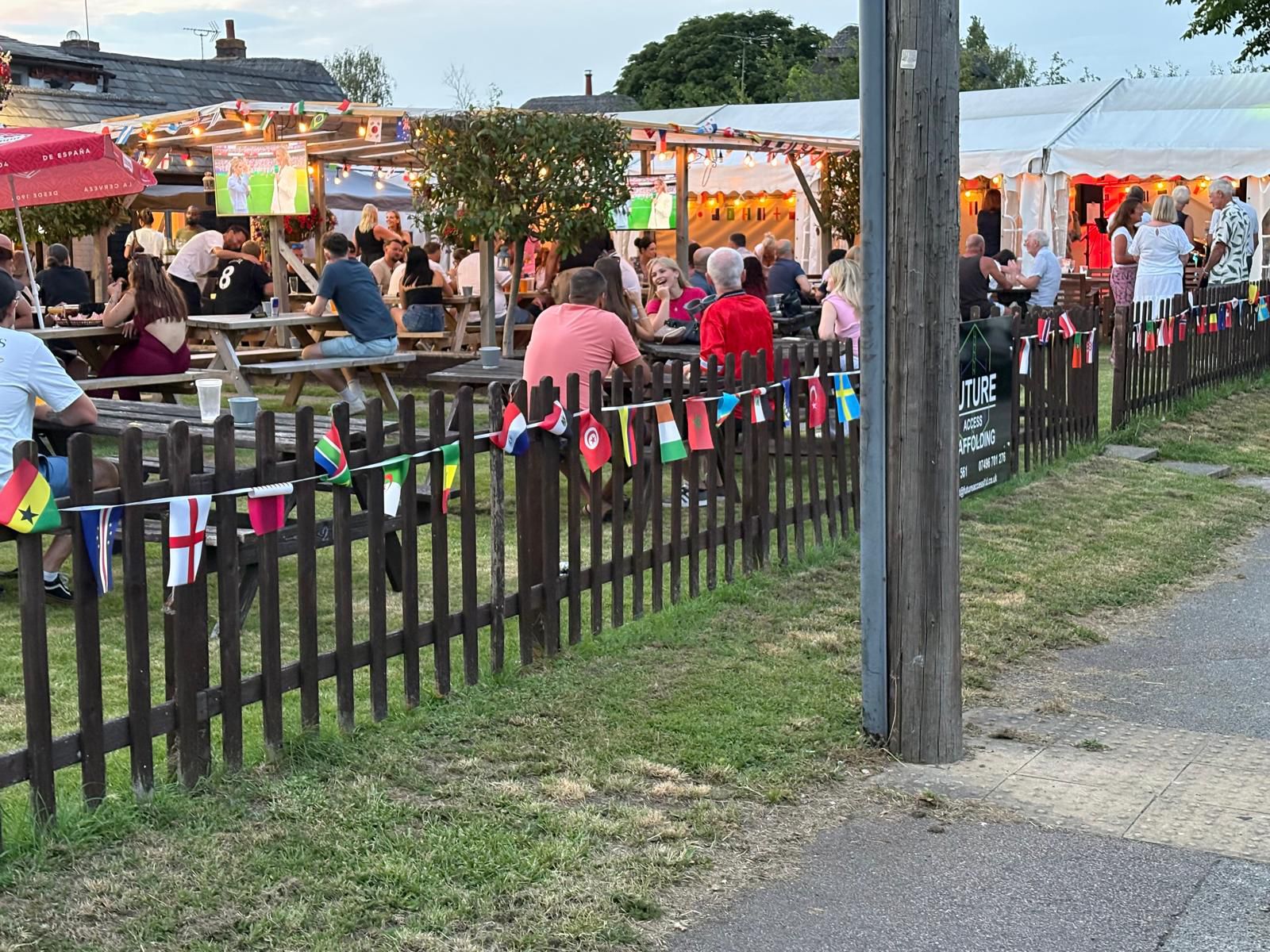 A large white marquee set up on the pub lawn, open along one side with tables inside